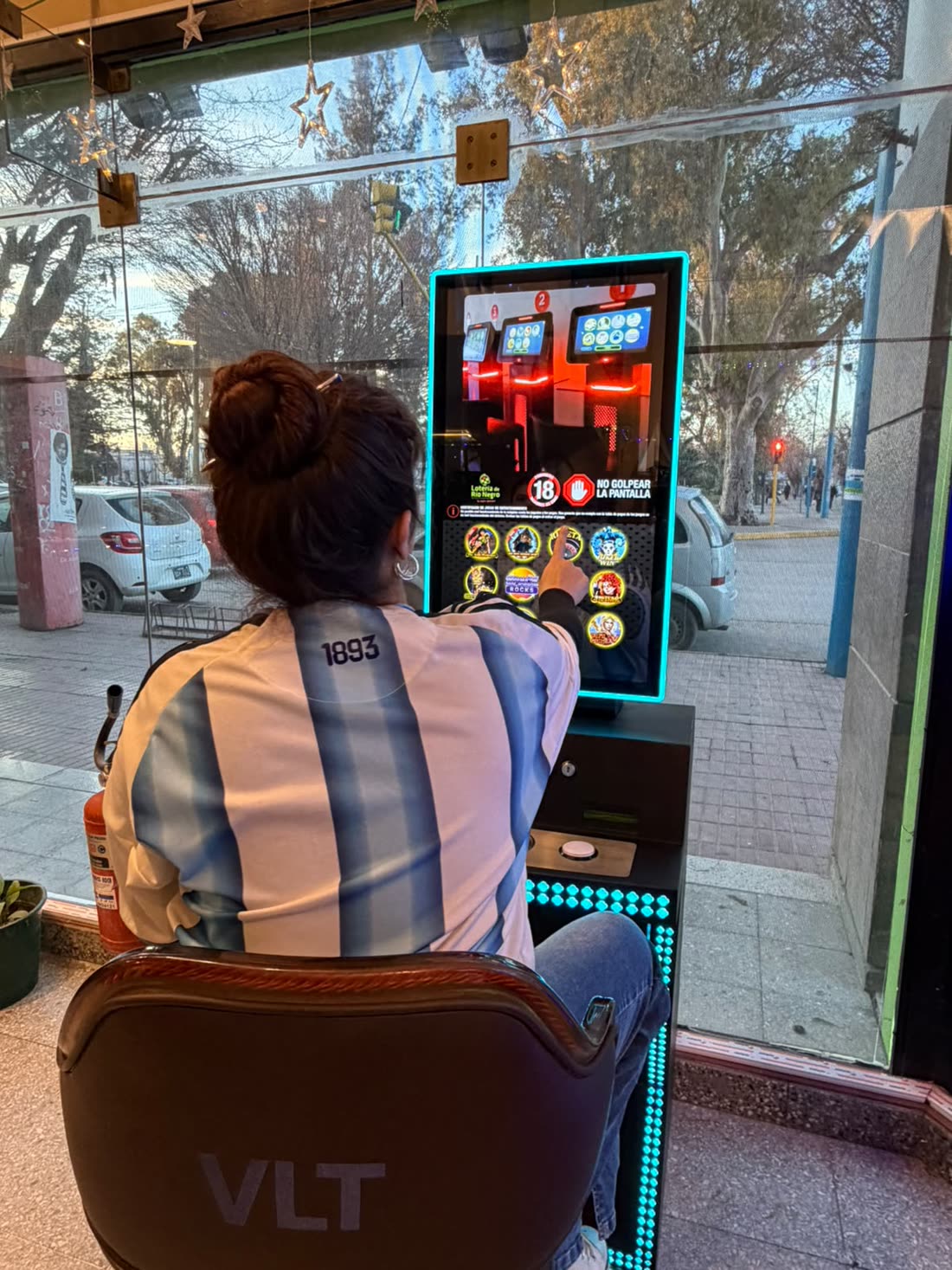 Una persona jugando en una de las máquinas de la agencia, con el juego en pantalla
